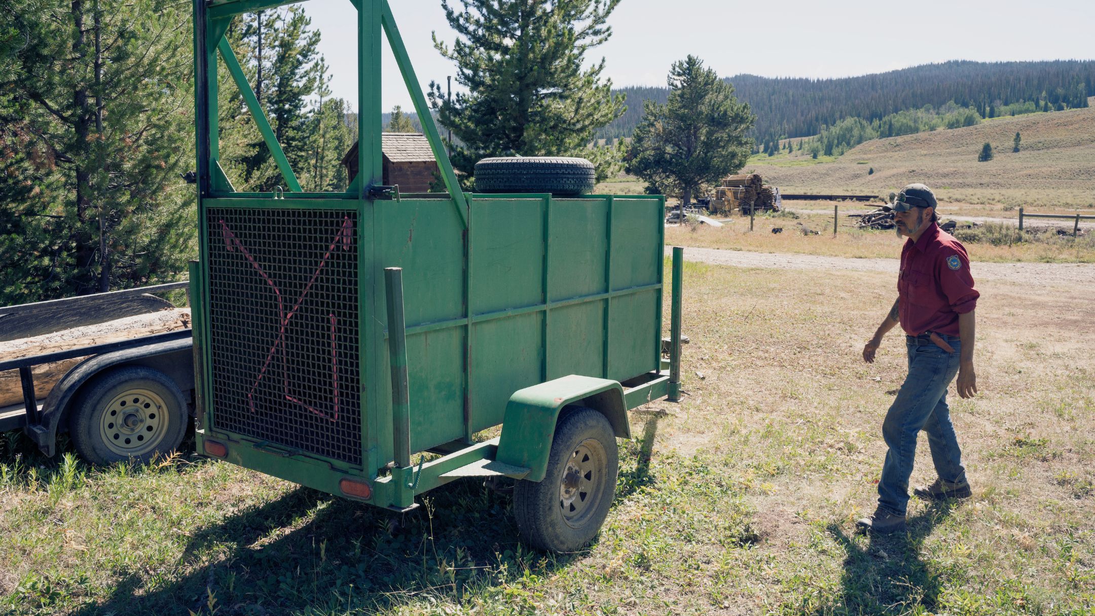 A Wyoming Game and Fish employee approaches an empty bear trap trailer used to capture grizzly bears for management action.